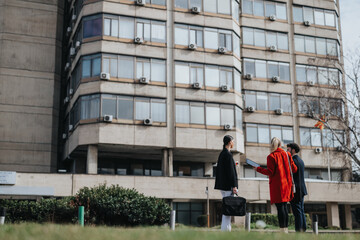 Three professionals engaged in a discussion outside a modern office, depicting teamwork and corporate lifestyle.