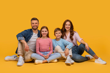 A family consisting of parents and children sitting on the floor, arranging themselves in a pose...