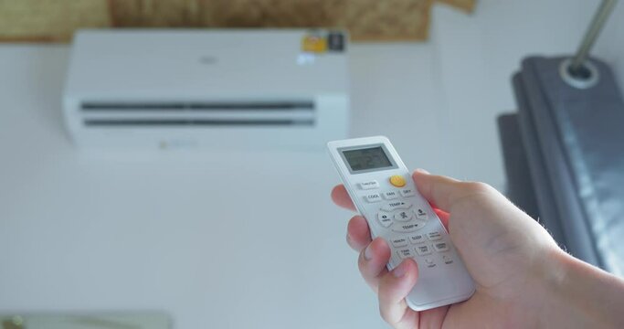 Human hand activating air conditioner with remote control counters heat effectively Air conditioner offers respite cooling homes. Air conditioner use elevates comfort making summer bearable.