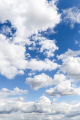 Beautiful light blue sky with many white fluffy cumulus clouds in sunlight, background texture, heaven