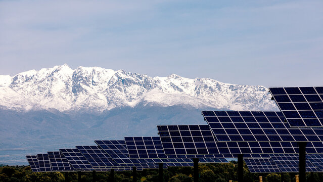 Solar panels with snow-capped mountains in the background