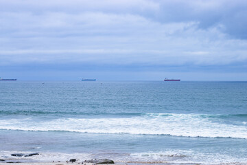 three cargo ships in the distance at sea