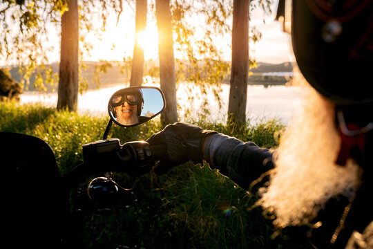 Senior Biker's Reflection in Motorcycle Mirror at Sunset