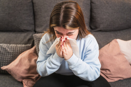 Young woman with a cold sitting on a couch at home