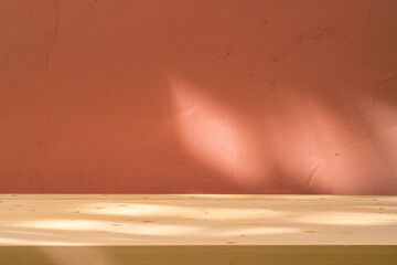 Table with coral pink wall and sun light reflections. Food, product or cosmetic background.