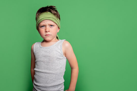 Boy with serious expression on green background