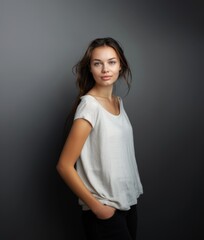 Obraz premium A brunette with wavy hair and a fleeting smile in light clothes on a gray background. Women's fashion and beauty, confident strong woman.