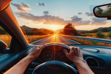 Close-up of drivers hands on steering wheel on summer road trip at sunset in vacation