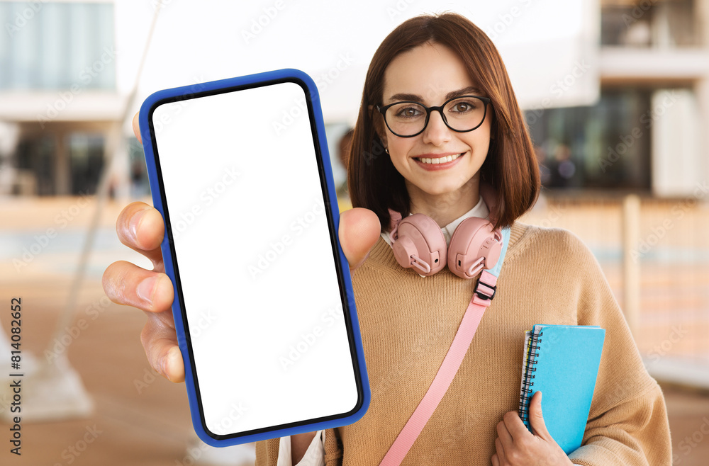 Aufkleber a woman student is holding up a modern smart phone with a blank screen in her hand. she appears to b
