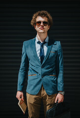 Stylish young man in a blue blazer posing confidently against a dark urban background, ready for a...