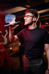 Joy and music. Happy young man is singing in karaoke nightclub