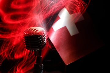 Microphone on a background of a blurry flag of Switzerland close-up. dark table decoration