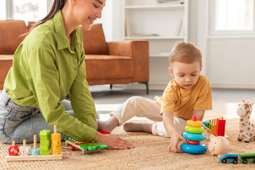 A woman is interacting with a child on the floor, engaging in play and nurturing activities. Both individuals are focused on each other, fostering a bond through shared moments of joy and laughter.