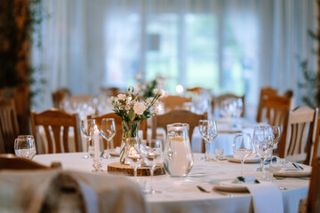 Valmiera, Latvia - August 25, 2023 - Rustic wedding reception table setting with white flowers, candles, and elegant glassware in a cozy venue...