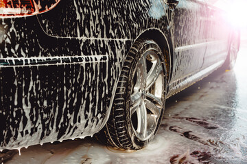 Applying foam for washing the car in bright sunlight