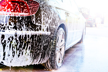 Applying foam for washing the car in bright sunlight