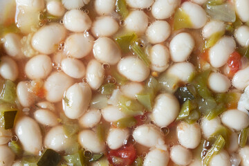 Overhead view of Spanish Round White Beans (Pochas) with freshly diced green peppers, succulent zucchini, ripe tomatoes, onions, garlic, and a drizzle of golden olive oil enriches the visual feast.