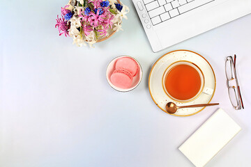Modern feminine desk, home office. Computer, hyacinth flowers and a cup of tea, macaroons on an...