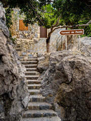 Staircase in Port De Sa Calobra leading to Torrent de Pareis canyon with a guidepost pointing the way, perfect for illustrating travel destinations, hiking adventures and tourist guidance in Mallorca.