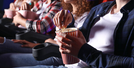 Fototapeta na wymiar Friends with popcorn watching movie in cinema
