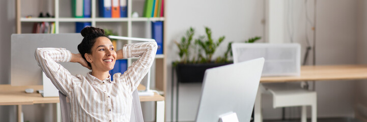 Happy female office worker leaning back on chair, relaxing after successful work at her workplace...