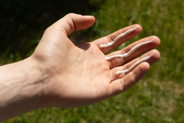 A person applying the correct amount of sunscreen for face and neck - three finger lengths.