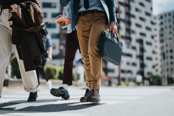 A group of business professionals with modern attire walking across a city street, depicting a...