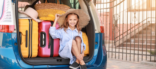 Little girl near car with packed luggage outdoors