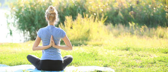 Beautiful young woman practicing yoga in park