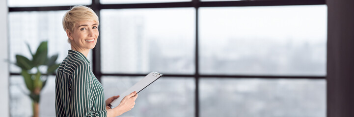 Successful Businesswoman Holding Folder Standing Near Window In Modern Office. Selective Focus, Copy Space