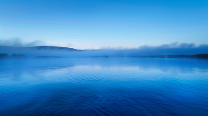 Fototapeta premium River fog at dawn, tranquil blue water fading into a misty horizon