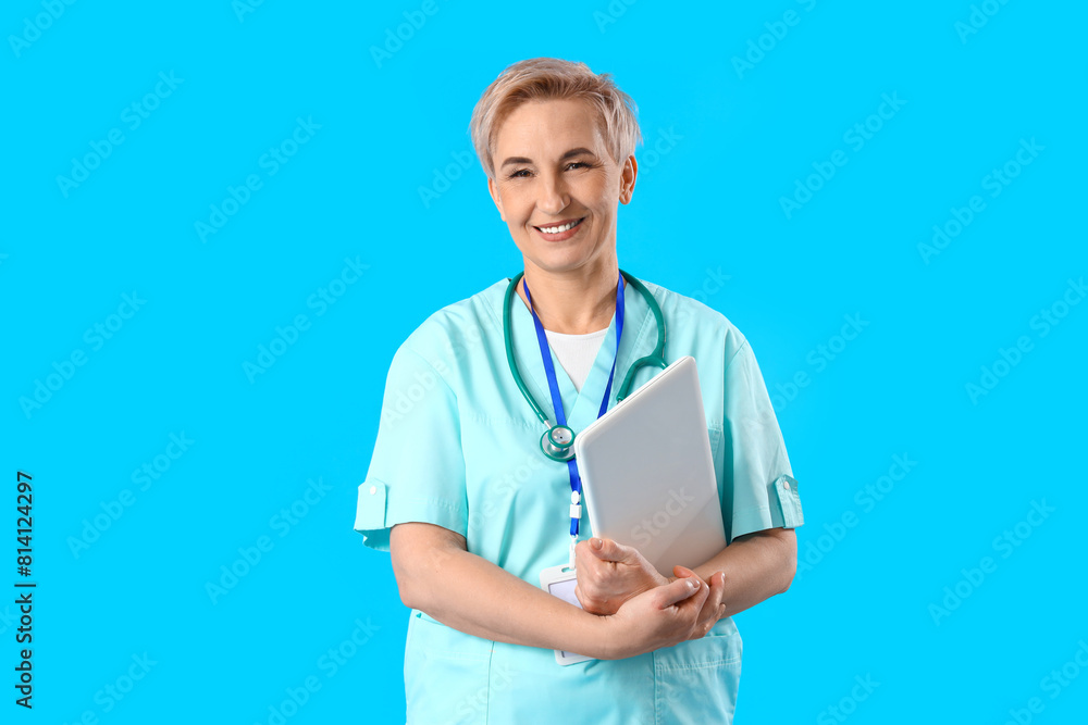 Canvas Prints Mature female nurse with laptop on blue background