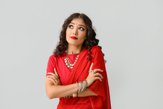 Beautiful thoughtful Indian woman in sari on grey background