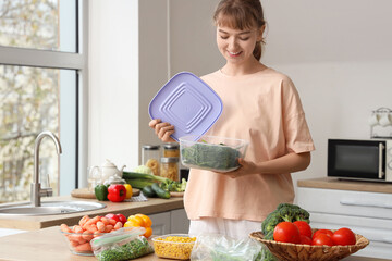 Beautiful young woman with vegetables for freezing in kitchen