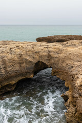 Views of Waves Crashing in on an Enclave Created by the Cliffside on a Hazy Day in Albufeira...