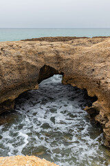 Views of Waves Crashing in on an Enclave Created by the Cliffside on a Hazy Day in Albufeira...