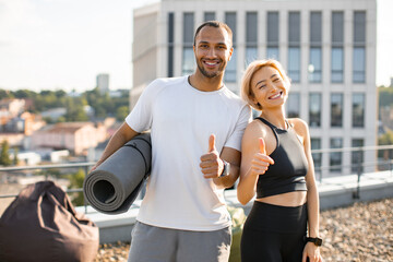 Young sporty man and woman resting after active sports warm-up. Portrait of happy multi-ethnic...