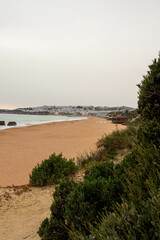 Cliffs Peaking Up Through the Ocean Near the Beach as Waves Crash in on During a Hazy Sunset in Albufeira Portugal
