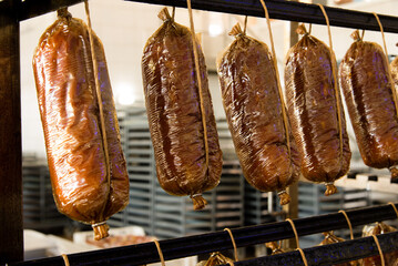 Production of dairy and meat products. Finished sausages, smoked cheese are hanging in a processing...