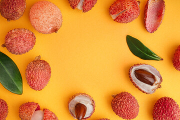 Frame made of tasty litchi fruit on orange background