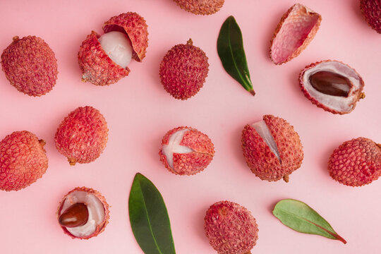 Tasty litchi fruit and leaves on pink background