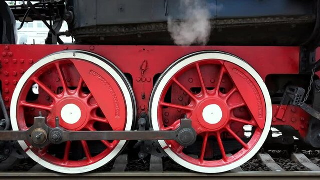 Close-up of a steam locomotive wheels at a railway station.