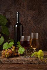 Still life with glasses of red and white wine and grapes on vintage wooden background..