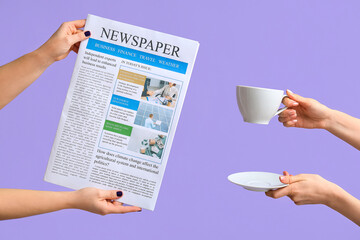 Female hands with newspaper and cup of coffee on lilac background
