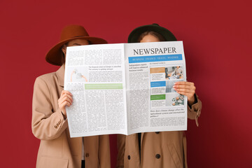 Women in cloak and hat with newspaper on red background