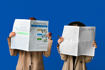 Women in cloak and hat with newspapers on blue background