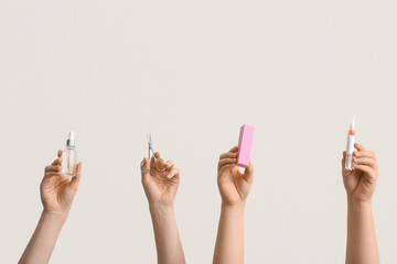Female hands holding bottle and pen of cuticle oil, scissors with buffer on white background