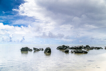 Tropical bay, paradise destination on the Cook Islands. Big stones on the beach  on tropical island Rarotonga. Blue sea with rocks during a sunny day.  Crystal clear water. Summer travel concept.