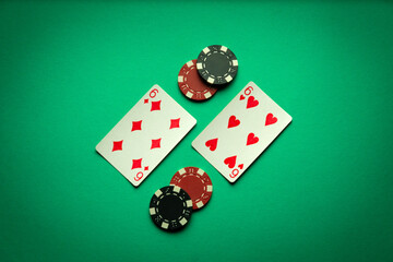 A gambling game of poker with a winning combination of one pair. Playing cards and chips on a green table in a poker club