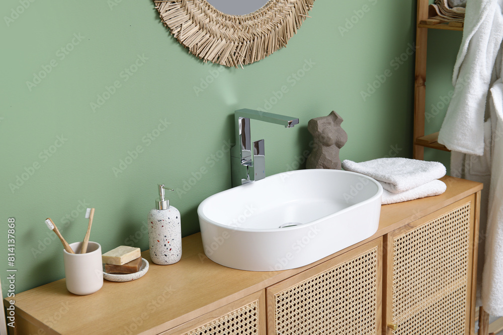 Poster Modern sink with bath supplies on countertop near green wall in bathroom